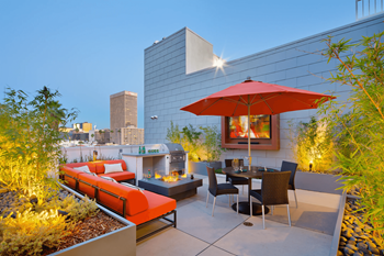 a terrace with a table and chairs and a red umbrella